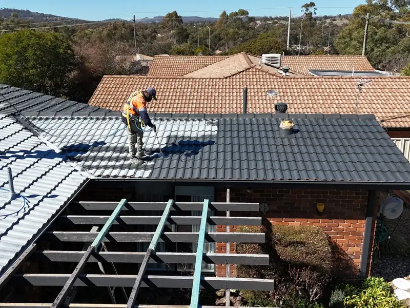 Two of our crew spraying the top coat onto a tiled roof