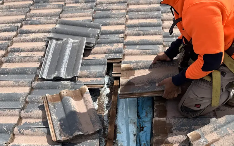 Our roofer lifting tiles to repair a section of a tiled roof